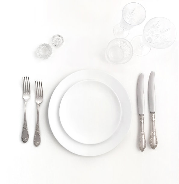全新的豪华白色陶瓷板，银色复古餐具从一个孤立的背景上俯瞰。前视图。婚礼、生日或聚会时餐桌上用的刀和叉。图片下载