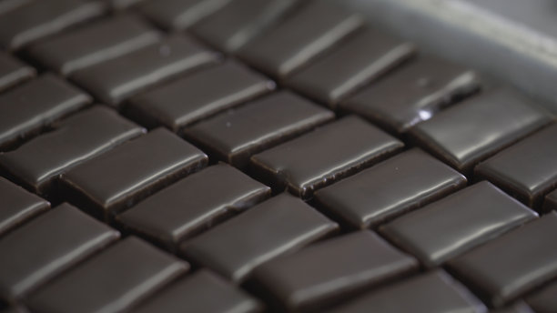 巧克力糖果被送到传送带上。糖果在传送带上。巧克力糖果在传送带上移动。糖果上面覆盖着巧克力图片下载