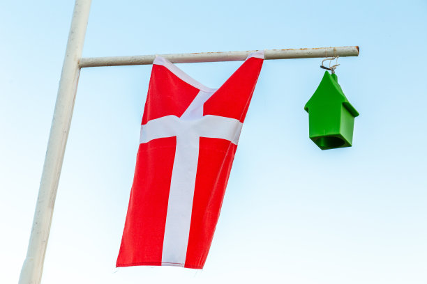 丹麦国旗，挂在一根杆子上，被风吹得半死。概念问题在国家。图片下载