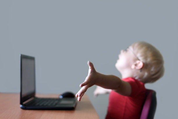 一个金发男孩在电脑前的模糊肖像。快乐，工作结束图片下载