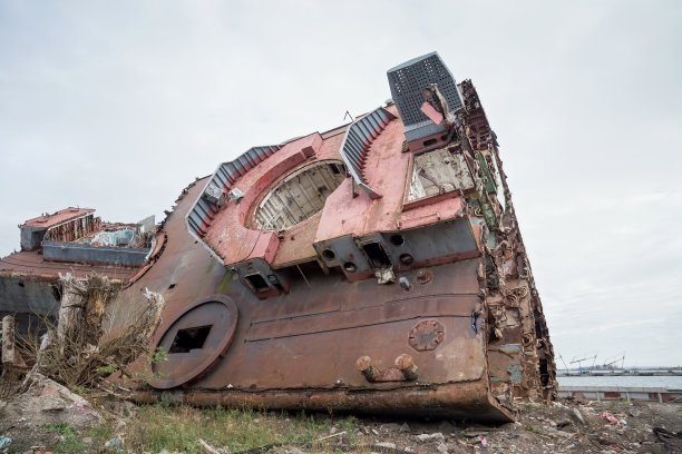 巨大的生锈的退役海运船的碎片被切断并留在岸上。图片下载