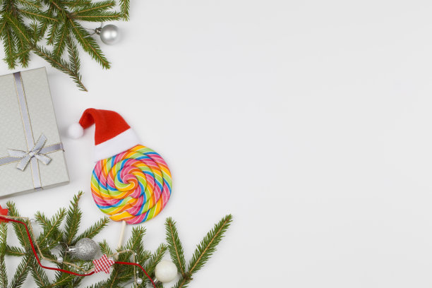 圣诞礼物，彩色的棒棒糖和冷杉树枝在白色的背景。节日的概念。图片下载