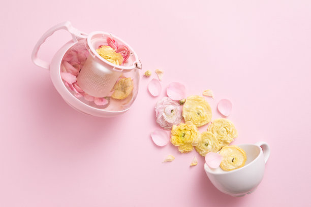 俯视图的草药茶从粉红色的茶壶倒进粉红色的背景杯。平的。下午茶时间的概念。图片下载