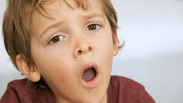 严肃的小男孩看着镜头打哈欠图片下载
