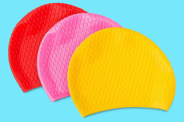 三种颜色的橡胶帽游泳在游泳池躺在绿松石的背景，概念图片下载