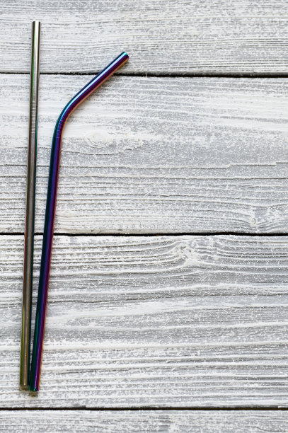 可重复使用的金属吸管，白色的木材背景。平放，俯视图，文本空间。图片下载