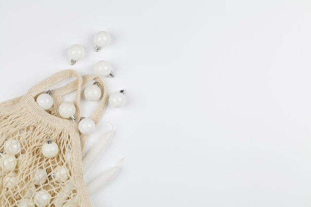 圣诞假日装饰灰色玩具在环保购物网袋白色背景与拷贝空间。图片下载