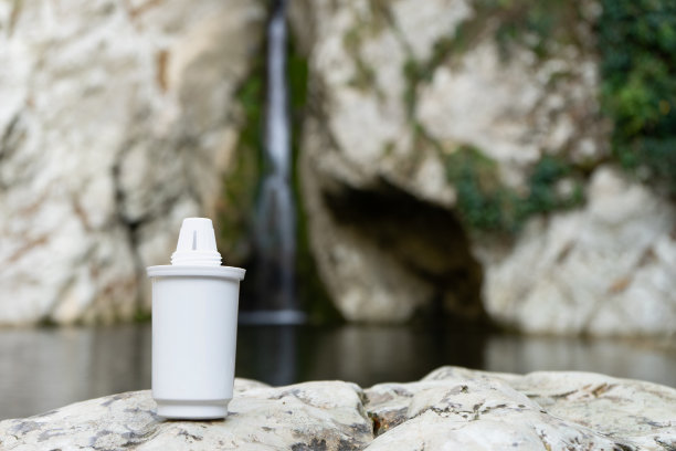 过滤器的水壶在一个山瀑布的背景。安全饮用或用于食品制备的洁净水的概念。图片下载