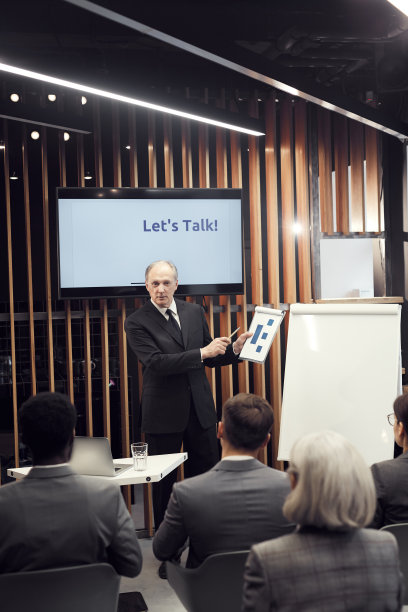 经验丰富的资深商人站在等离子屏幕上，指着剪贴板上的图表，同时教商业学生销售策略图片下载