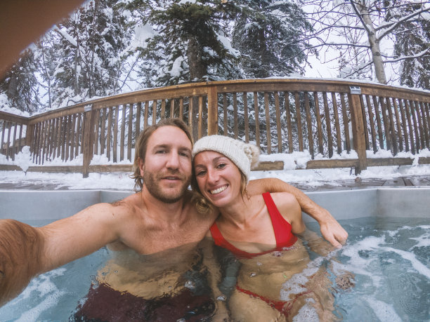 Young couple take selfie in SPA Hot Tub in winter surround by snow年轻夫妇在被雪包围的冬天里自拍SPA Hot Tub图片下载