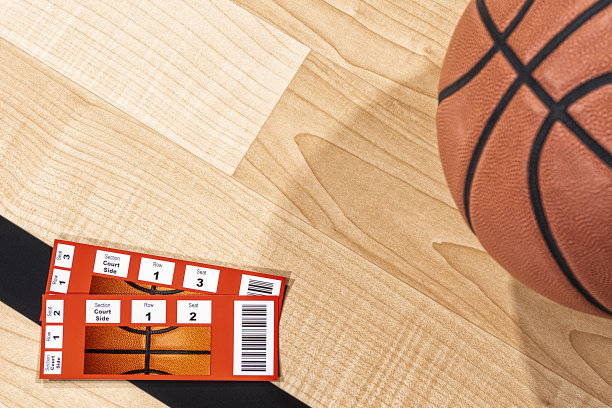 两张篮球球票和一个篮球放在赛场的木地板上图片下载