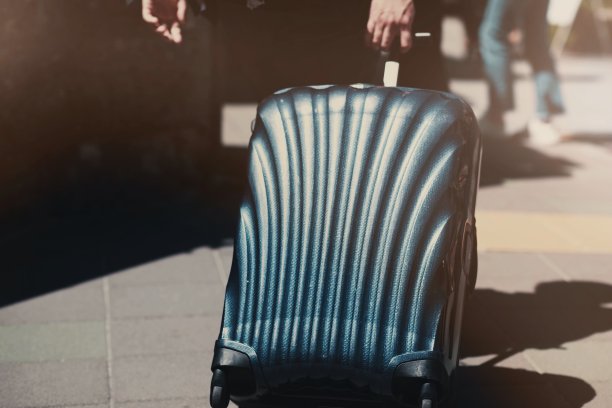 旅客拖着黑色的行李来到旅馆。图片下载