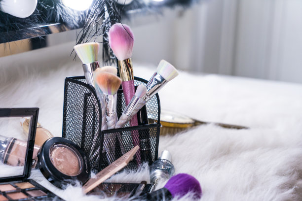 化妆刷和玻璃上的白色毛皮背景，美丽的概念图片下载