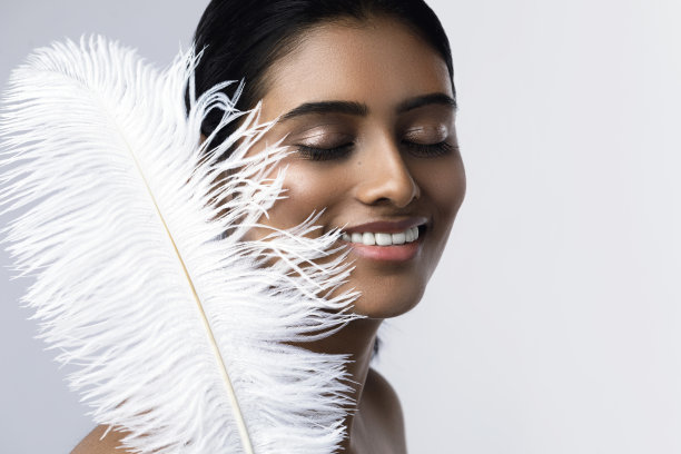 拿着柔软鸵鸟毛的年轻性感印度女人图片下载