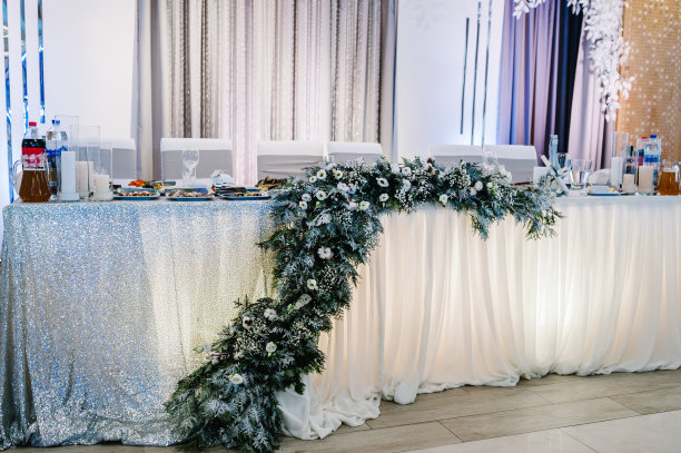 宴会厅的节日餐桌上装饰着冬天用皮草树枝构成的图案。新婚夫妇在宴会区域的餐桌。圣诞节冬季婚礼。事件。图片下载