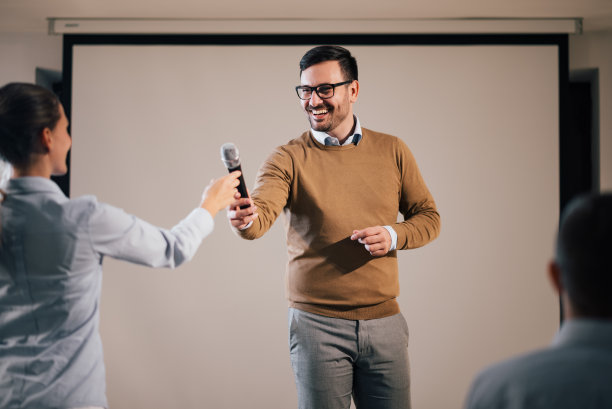 主持人微笑着给嘉宾演讲嘉宾麦克风。图片下载