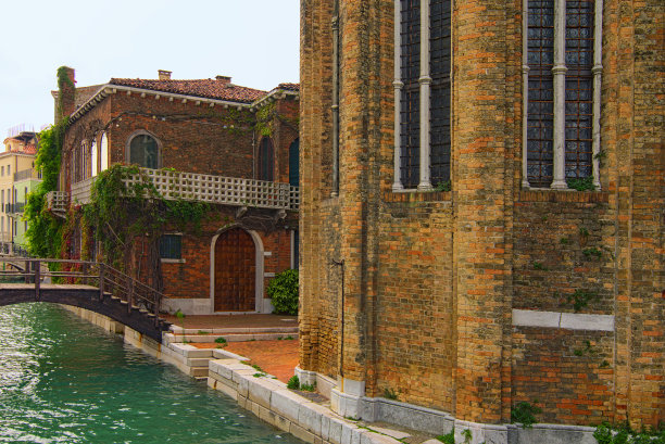 美丽的风景照片，威尼斯的非旅游部分。漂亮的砖建筑，有阳台。木桥上狭窄的运河与绿松石水。旅游和旅游概念。意大利的威尼斯图片下载