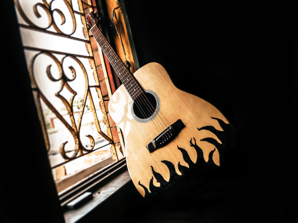 一把原声吉他放在古老的窗户旁边，柔和的阳光从窗户里射进来。怀旧的吉他和弦。夏天的旋律背景。关闭了。图片下载