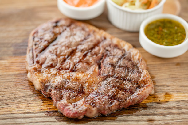 半熟烤牛排肋眼片配酸菜和两种酱汁。在木板上工作烧烤餐厅的菜单，一系列不同肉类的照片。图片下载