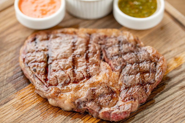 半熟烤牛排肋眼片配酸菜和两种酱汁。在木板上工作烧烤餐厅的菜单，一系列不同肉类的照片。图片下载