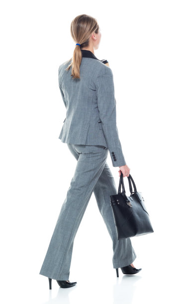 后视图/一人/全长20-29岁的成年美丽的白人女性/年轻女性商人/商人步行穿着西装，拿着公文包/包/咖啡杯图片下载