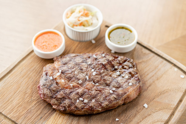 半熟烤牛排肋眼片配酸菜和两种酱汁。在木板上工作烧烤餐厅的菜单，一系列不同肉类的照片。图片下载