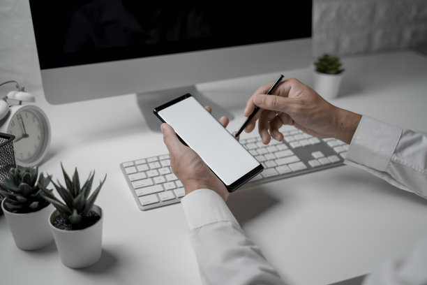 近距离拍摄的商人在办公室拿着智能手机与空白屏幕图片下载