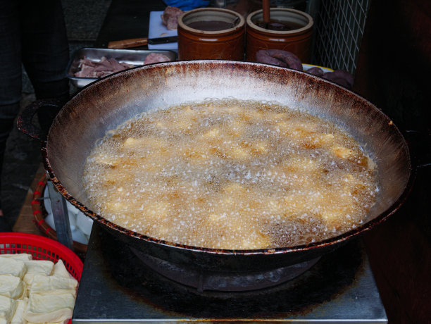 油炸豆腐在大锅或炒锅里装满油。越南街头小吃摊，垃圾食品不健康。图片下载