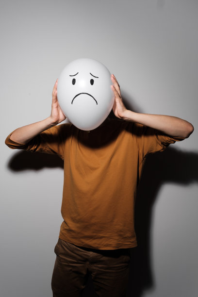 一个男人拿着白色气球带着悲伤的微笑面对情绪而不是头部。消极思维的概念。图片下载