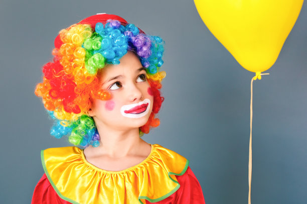 快乐小丑女孩的肖像靠近黄色的热气球图片下载