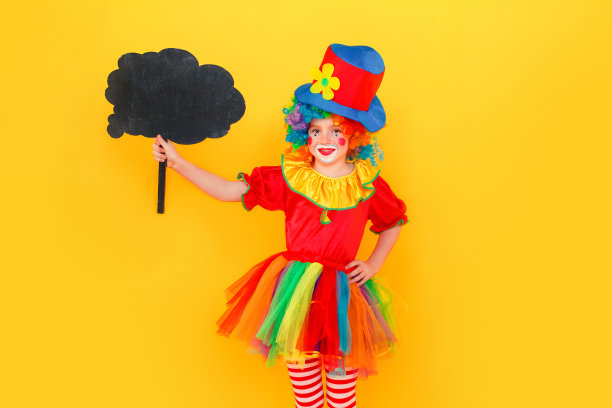 幸福的女孩穿着小丑服装和帽子拿着黑色的桌子图片下载
