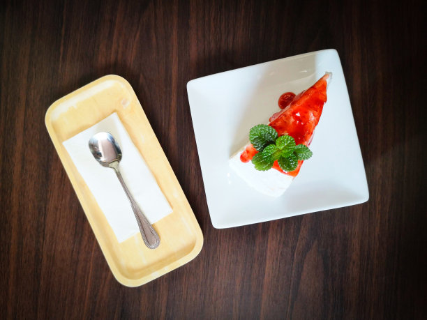 背景白盘上草莓酱黑纱蛋糕片/薄荷叶蛋糕片图片下载