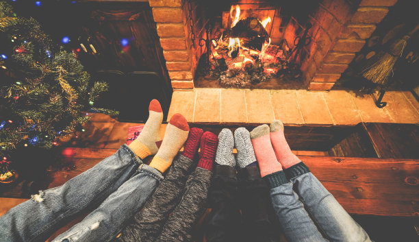 脚的观点，幸福的家庭躺下旁边的壁炉和圣诞树穿着温暖的羊毛袜子-冬天，节日，爱和舒适的概念-关注脚图片下载