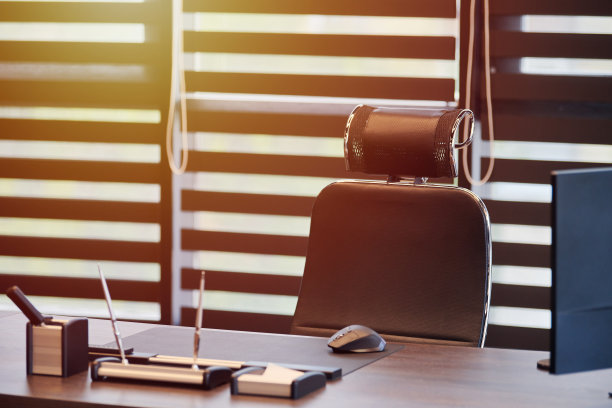 商业办公场所。阳光在工作场所为首席，老板或其他员工。桌子和舒适的椅子。光线透过半开的百叶窗图片下载