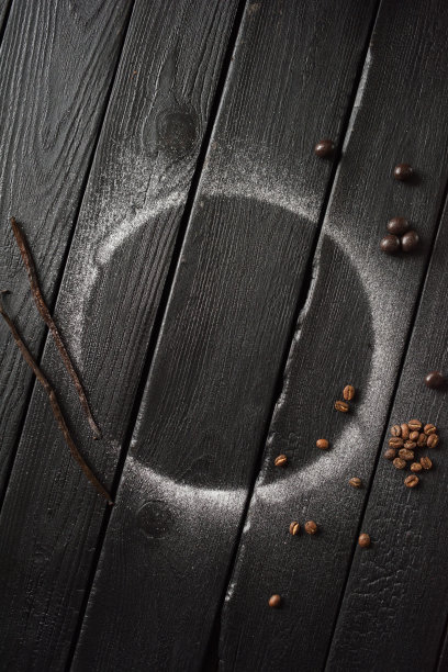 圆糖霜踪迹，香草豆荚和咖啡豆在空的黑色桌子上俯视图片下载