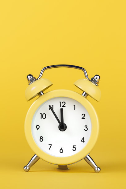 黄色背景上的黄色圆形闹钟。图片下载
