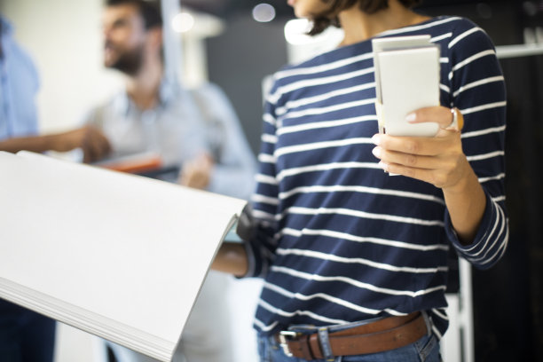 一个认不出来的女人一手拿着瓷砖样品，一手拿着目录图片下载