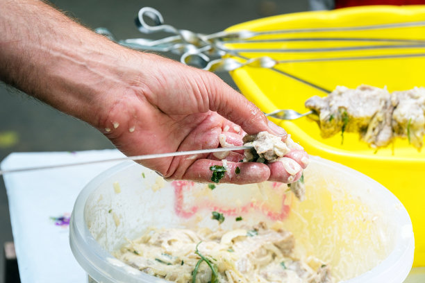 男人把腌过的肉串在烤肉串上图片下载