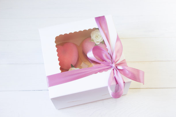 奶油蛋糕礼盒。粉色玫瑰装饰的心形蛋糕。粉色蝴蝶结，白色底色，甜蜜浪漫的礼物图片下载