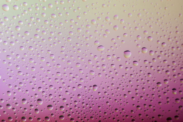 玻璃上水滴的特写。彩虹背景，彩色抽象图案。图片下载