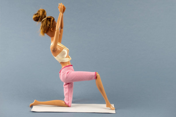 在灰色背景上的瑜伽姿势的塑料娃娃图片下载