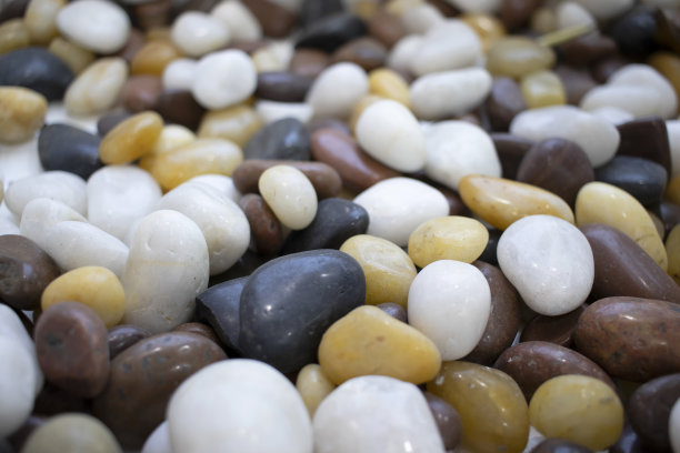 彩色圆卵石在阳光下黑、白、黄五彩缤纷。设计师散景背景与模糊的背景抽象。海滩上五颜六色的鹅卵石特写。图片下载
