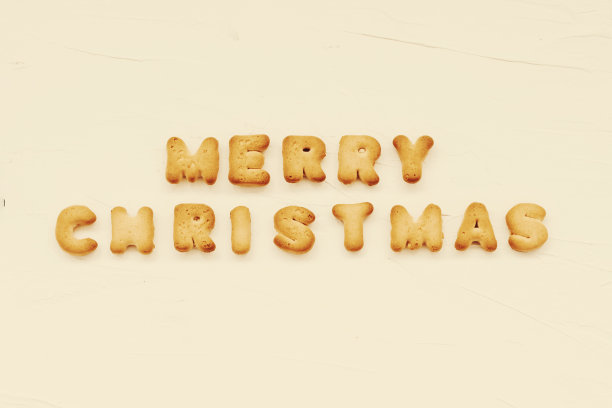 “圣诞快乐”这几个字写在饼干字母上，白色的背景，复古的深褐色的照片。图片下载