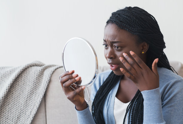 失望的非洲裔妇女望着镜子，摸着自己的皮肤图片下载