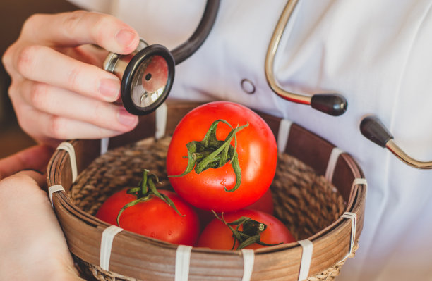 医生拿着听诊器检查一个西红柿的收获质量控制概念图片下载