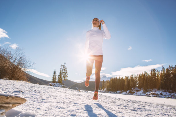 妇女在冬季进行越野跑，在雪地上慢跑图片下载