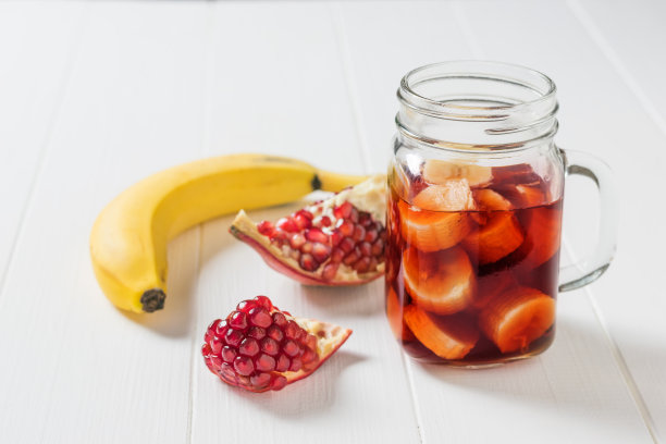 白色桌子上放着香蕉片和石榴汁的杯子。图片下载