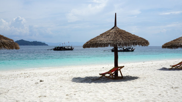 户外蓝色海洋背景的海滩上，天然的叶子热带阳伞图片下载