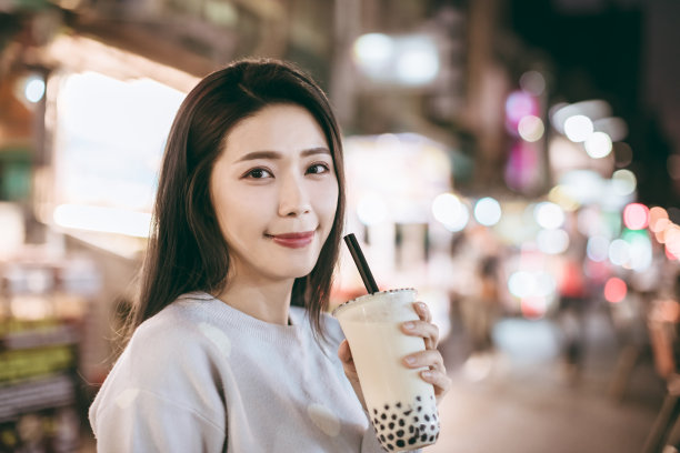 在夜市品尝珍珠奶茶和街头小吃的亚洲女性图片下载