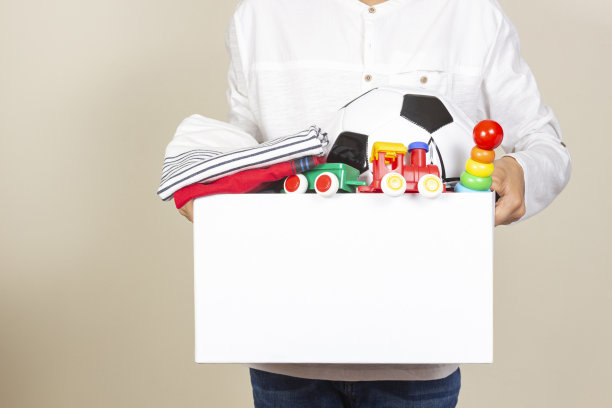 捐赠的概念。孩子们拿着捐赠箱，里面装着衣服、书籍、学习用品和玩具。杂志拼贴风格，以浅绿色为背景图片下载